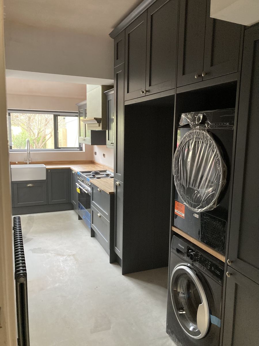 Washer and dryer stacked within full-height dark cabinetry
