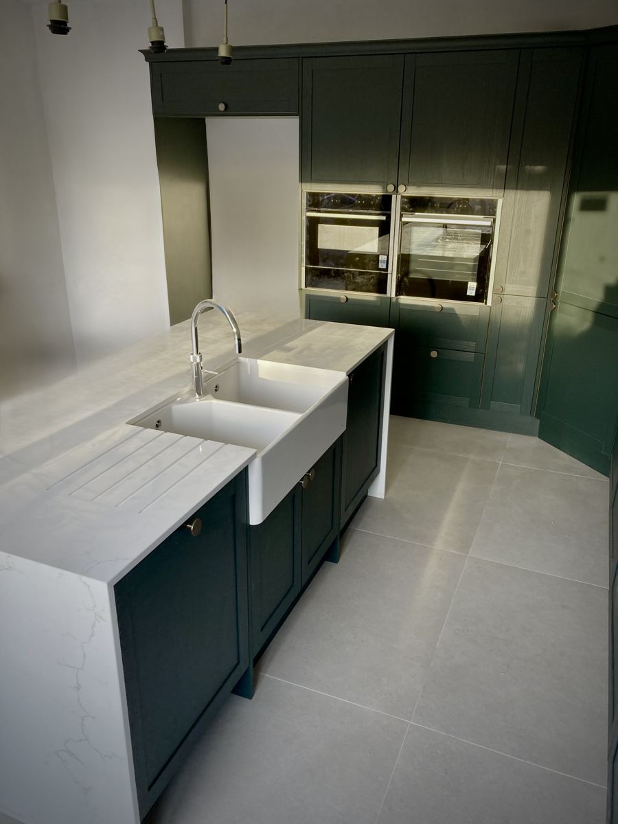 Double belfast sink with drainer grooves cut into the quartz island worktop