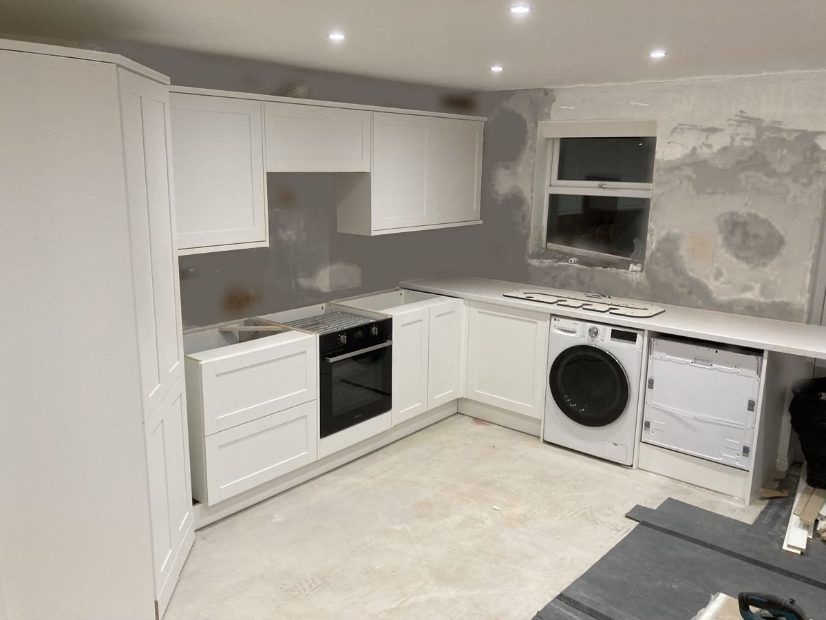 White shaker cabinetry and worktops installed against bare plaster mid-project