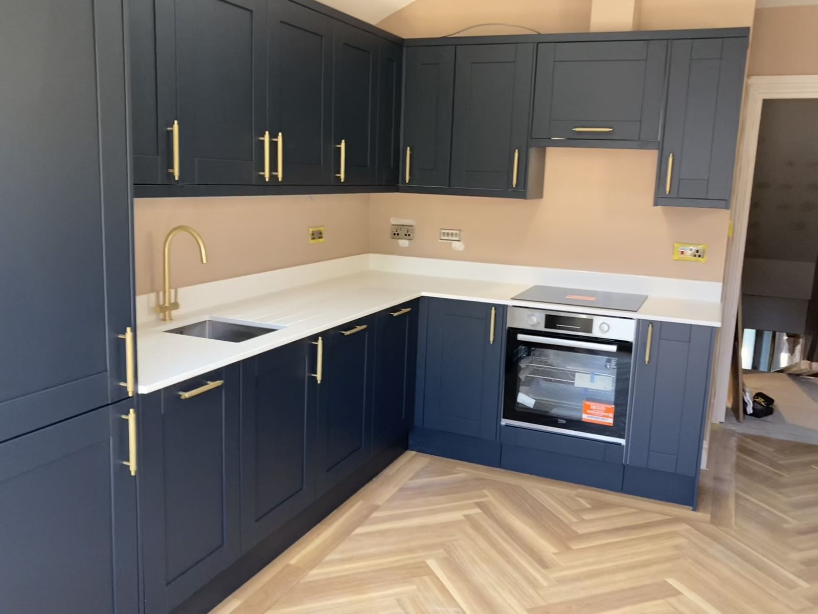 Navy blue shaker kitchen with brass hardware and herringbone flooring, Pontcanna