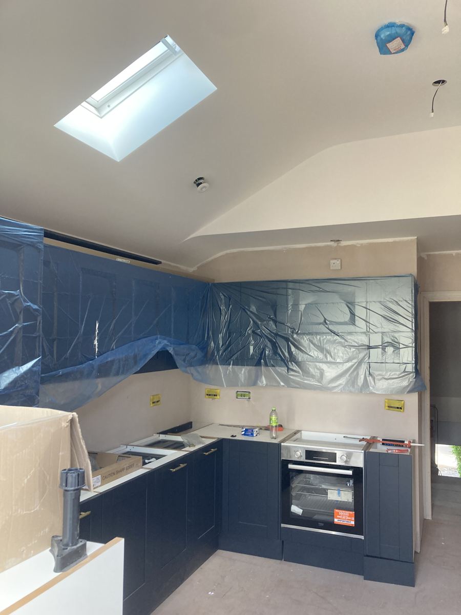 Navy shaker units installed beneath the new vaulted ceiling and skylight, protective film still on