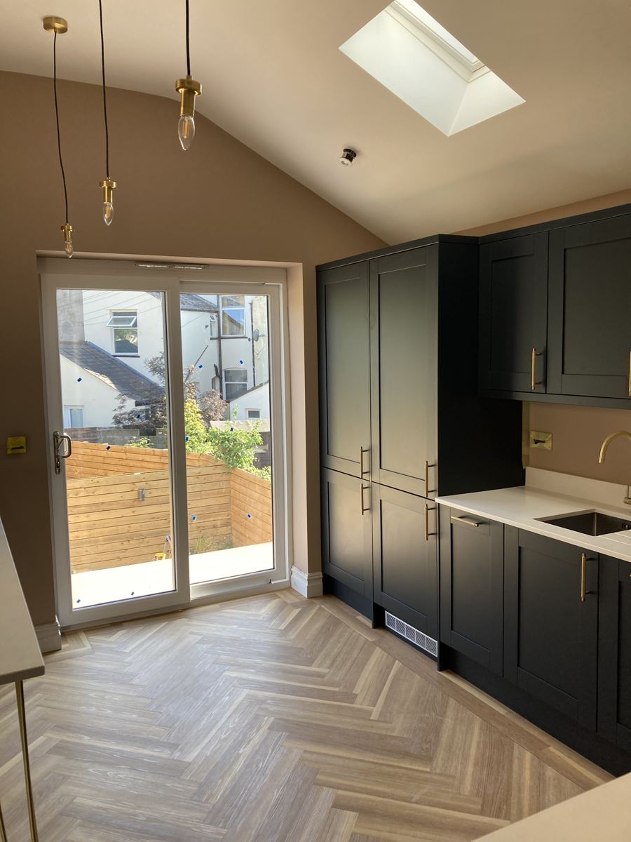 Vaulted ceiling with skylight and brass pendants above the finished navy shaker kitchen, Pontcanna